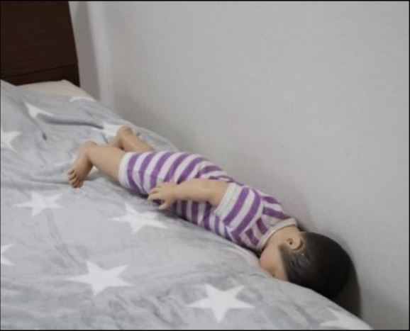 壁とベッドに赤ちゃんが挟まれている
